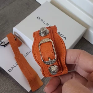 Balenciaga armband - Jättefin Balenciaga armband i helt perfekt skick! I princip oanvänt. Jättecool orange färg. Storlek S. Kommer med lådan och kort. 