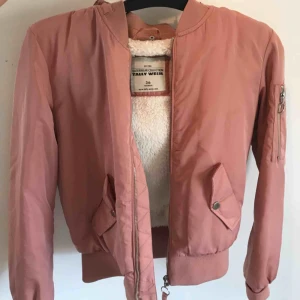  - Rosa bomberjacka med fluff inuti. Luvan går att ta av/på. I stort sätt aldrig använd. 