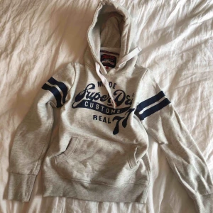  - Grå hoodie från superdry. Lyxigt material med blå detaljer. 