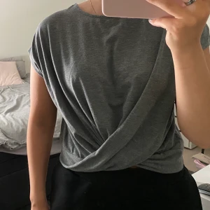 Topp  - En fin grå topp från NAKD med knyte där fram. Aldrig använt! passar fint nu till vår och sommar. Frakten står kunden själv för :)