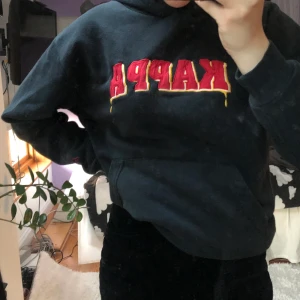 Kappa hoodie svart - Vintage Kappa hoodie med gult och rött tryck. Köpt secondhand men är fräsch. Passar storlek s/m. Frakt ingår ej🥰