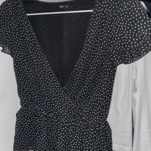 Prickig topp - Söt prickig urringad topp med volang nedtill.