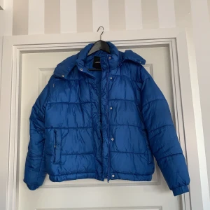 Kornblå dunjacka från Monki  - I storlek 40! Luvan sitter fast i en dragkedja så den går att ta av ifall man vill det 