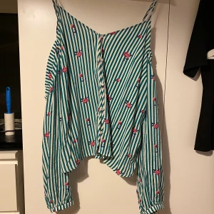 Off-shoulder topp - Randig långärmad off shoulder topp med blommor på. Knappar på framsidan