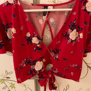Söt blus från HM! - Blommig croppad topp med knytning i ryggen! Inhandlad för ett par år sen men nästan aldrig använd. Stretchigt material med bra kvalitet. Storleken är L men väldigt justerbart pga knytningen! Passar mig som kan ha både S och M. 
