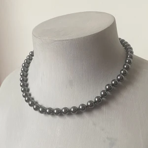 Halsband hematit med gulddetalj - Snyggt och elegant hematithalsband med en fin gulddetalj vid låset. Perfekt för att ge en touch av klass till vilken outfit som helst. Stenarna är jämnt fördelade och ger en stilren look.