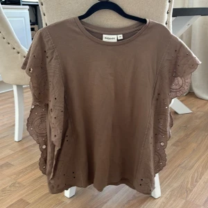 Brun tröja - En brun T-shirt med volger på sidorna i stl M från Kappahl i andvänt skick