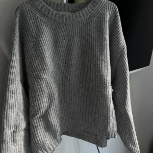 Grå stickad tröja från H&M - Säljer en supermysig grå stickad tröja från H&M. Den har en ribbad design och långa ärmar, perfekt för kyliga dagar. Tröjan är i storlek M och passar perfekt för både höst och vinter. Den är i använt skick och redo för en ny ägare!