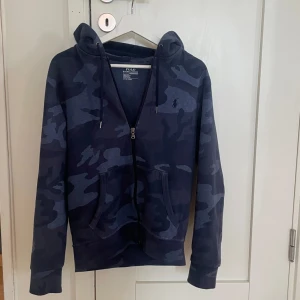 Ralph lauren hoodie - Tja, säljer den här riktigt feta Ralph lauren hoodien i en ”camoflauge” colourway. Ny pris på hoodien är runt 1500-2000 mitt pris är 599kr. Han på bilden är 178 väger 64 kg. Väldigt bra skick! Kom om vid frågor eller intresse!
