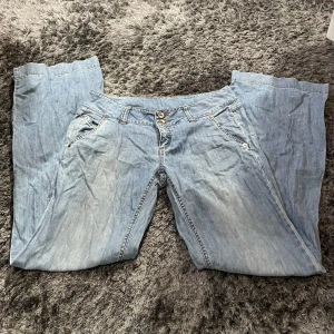 Ljusa jeans från Vero Moda - Säljer ett par ljusa jeans från Vero Moda. De har en klassisk femficksdesign med knapp och dragkedja framtill. Jeansen är i en avslappnad passform och ser ut att vara i bra skick. Perfekta för en casual look!