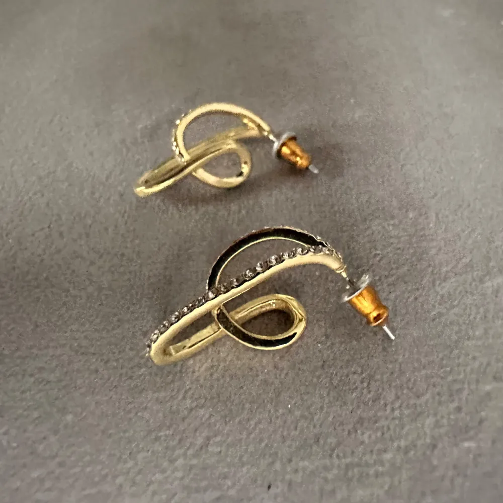 Guldpläterade kristall örhängen Vågiga former med mycket glans Mått 22 mm i längd Elegant formspråk med smala silhuetter Styla med smala kedjor och ringar lager på lager. helt oanvända och nypris är 379kr!. Accessoarer.