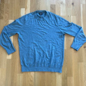 Blå tröja från H&M - Säljer en stilren blå tröja från H&M i storlek L. Den är slim fit och tillverkad i 100% bomull, vilket gör den både bekväm och lätt att bära. Perfekt för både vardag och lite finare tillfällen. Tröjan har långa ärmar och en klassisk rund halsringning.