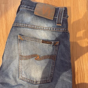 Blå jeans från Nudie Jeans - Säljer ett par snygga blå jeans från Nudie Jeans. De har en klassisk straight fit och är i en härlig blå färg med lite slitningar för en cool look. Perfekta för både vardag och fest! Storlek 30/34 men är uppklipta till att passa någon runt 180-185