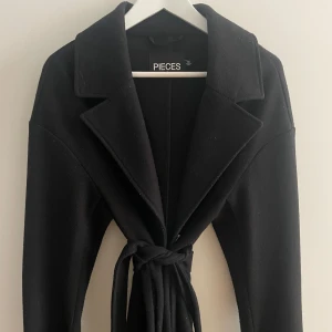 Kappa - Svart kappa med Bälte i midjan, man kan ta av det om man vill ha den rak istället🥰