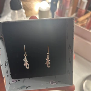Silvriga ödleformade örhängen - Säljer ett par unika och coola silvriga örhängen formade som små krokodiler 🐊 . Perfekta för att ge din outfit en rolig och annorlunda touch. De är i nyskick. Passar perfekt för både vardag och fest!