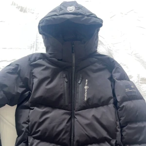 Sail Racing Vinterjacka - Svart Sail Racing vinterjacka i storlek S/M, i mycket fint skick. Varm och perfekt för kalla vinterdagar, med en enkel och snygg design. Jackan har justerbar huva, dragkedjefickor och är både vind- och vattentät. Passar bra för både vardag och utomhu
