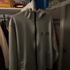 Hugo Boss zip up - Storklek M, Grå, använd ett par gånger, Bra kvalitet och inte alls sliten. Den har en luva. Varm och skön till vintern. Om mer info skriv privat. 