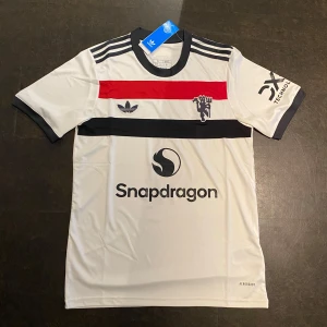 Manchester United fotbollströja - Manchester uniteds tredjetröja denna säsongen. Retro inspirerad och riktigt snygg. Inget namn på ryggen. Bara clean.