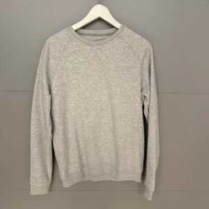Grå sweatshirt från Pier One - Säljer en stilren och bekväm grå sweatshirt från Pier One. Perfekt för både vardag och mysiga hemmakvällar. Tröjan har långa ärmar och en klassisk rund halsringning. Den är i bra skick och passar till det mesta i garderoben.