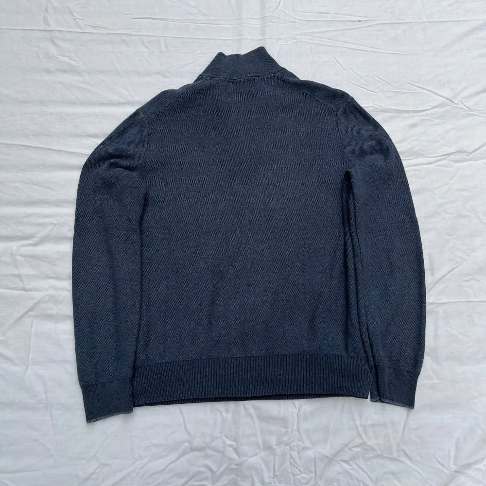 Knappt använd och väl omhändertagen. Stickad half-zip från Polo Ralph Lauren. Tillverkad i bomull i en texturerad stickning samt prydd med den ikoniska polospelaren på bröstet.                                              Butikpris: 2199kr. Stickat.