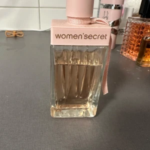 INTIMATE Eau de Parfum från Women'secret - Säljer en elegant och sofistikerad parfym från Women'secret, INTIMATE. Flaskan har en stilren design med en ljusrosa kork och ett matchande band. Doften är skapad av Jérôme Di Marino och kombinerar toner av tonkaböna, vita blommor och mysk. Perfekt för den som vill ha en modern och feminin doft med en känsla av sensuell mystik. Doftar precis som Carolina herrera good girl