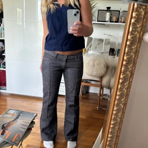 Grå bootcut jeans - Säljer ett par snygga grå bootcut jeans. De är lågmidjade och har en klassisk femficksdesign med knappar bak. Perfekta för en avslappnad men stilren look. Passar bra till både vardag och fest!