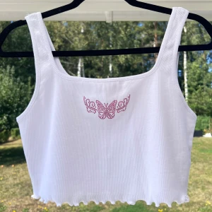 Ribbat vitt linne - Croppat ribbat linne med rosa strass-detalj på bröstet. Från Misslisibells kollektion med NA-KD 🌸 Aldrig blivit använt då det är lite för stort för mig 🌟  (ALDRIG ANVÄNT)  Längd: 37 cm Axel: 27 cm Byst: 78 cm