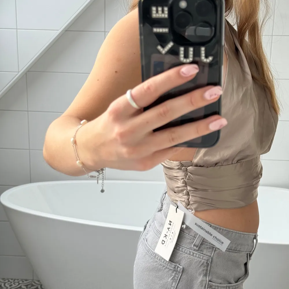 Säljer denna helt nya satin topp från NAKD, prislappen är kvar och toppen är aldrig använt🌸 så snygg champange färg och fin till lågmidjade jeans!. Toppar.