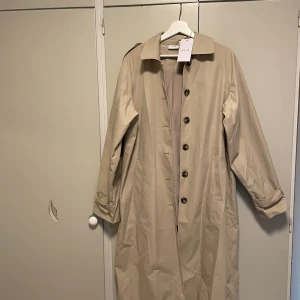 Lång beige kappa  - Lång kappa/trenchcoat från vila i nyskick. Storlek 38.💞