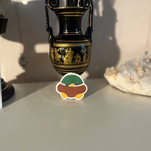 Söt klistermärke med anka - Det här är ett gulligt klistermärke föreställande en anka med en grön och brun kropp. Perfekt för att dekorera din laptop, anteckningsbok eller mobilskal. Klistermärket har en enkel och charmig design med klara färger som verkligen poppar!