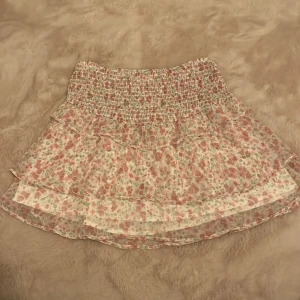 Blommig kjol från Gina Tricot - Säljer en superfin blommig kjol från Gina Tricot i storlek 146/152. Kjolen har ett elastiskt midjeband och volanger som ger en söt och lekfull look. Perfekt för sommarens alla äventyr! 🌸 kjolen när i nyskick använd ungefär 3 gånger. Kjolen är stor i storleken så den är typ i storlek 1-2 storlekar större