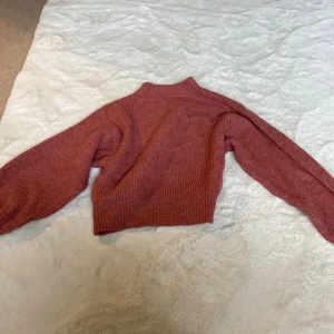 Röd stickad tröja - Säljer en supermysig rosa stickad tröja som är perfekt för kyliga dagar. Den har en hög krage och långa ärmar, vilket gör den extra varm och skön. Tröjan är i bra skick och passar perfekt till både vardag och fest. Perfekt för höst och vinter!