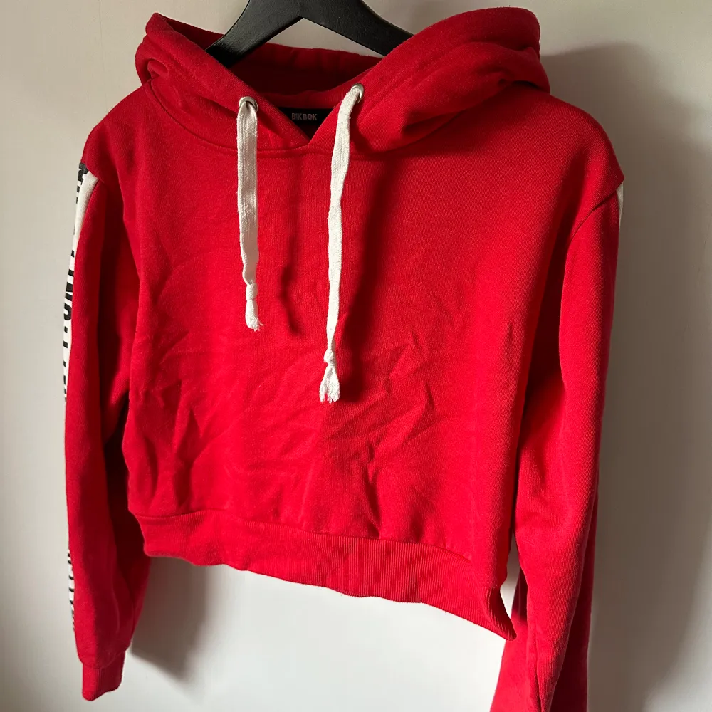 Croppad röd hoodie från BikBok i storlek S. Använd några gånger, bra kvalitet och mjukt material inuti. Text på ärmarna. Normal i storleken. . Hoodies.