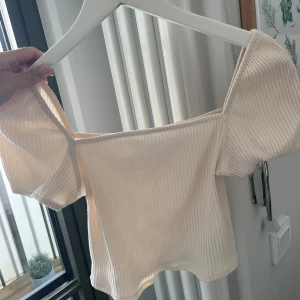 Beige ribbad offshoulder topp från H&M - Säljer en superfin beige ribbad topp från H&M. Den är offshoulder och har en tight passform. Toppen är i storlek S och är i nyskick. 