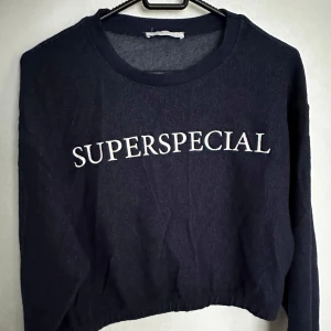 Mörkblå tröja med text från Zara - Säljer en mörkblå cropped tröja från Zara som är använd en gång. Tröjan är långärmad och har en avslappnad passform därmed storleken är Small-Medium . Perfekt för en casual look!