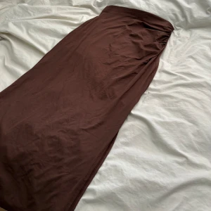 Långkjol - En brun långkjol/midikjol, beroende på om man har den lågmidjat eller högmidjat :) superskönt i materialet och luftig. Den har en slits på den vänstra sidan av kjolen vilket gör den lätt att gå i. Bara använd några få gånger, som ny.