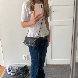 Gina Young handväska - Säljer en svart liten handväska med en stjärna på! Den har två styckna innerfack som man kan se på bild två, Ny pris 230kr, priset kan diskuteras!💕