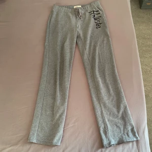 Grå mjukisbyxor från Hollister - Säljer ett par superbekväma grå mjukisbyxor från Hollister. De har en fin form med resår och snörning i midjan för extra komfort. Perfekta för mysiga dagar hemma eller en avslappnad dag ute. 