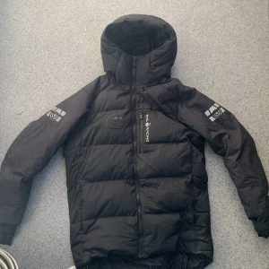 Svart dunjacka från Sail Racing - Säljer en svart dunjacka från Sail Racing i storlek medium. Jackan är perfekt för kalla dagar med sitt 500 fill power dunfoder. Den har två vanliga fickor och en bröstficka utifrån och även en inne Jackan är i bra skick och redo för vinterns äventyr!