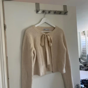Stickad kofta zara - En så så fin stickad tröja med rosett från zara. Storlek L men skulle säga en S. Köpt på plick men kommer tyvärr inte till användning. Cremefärgad. 