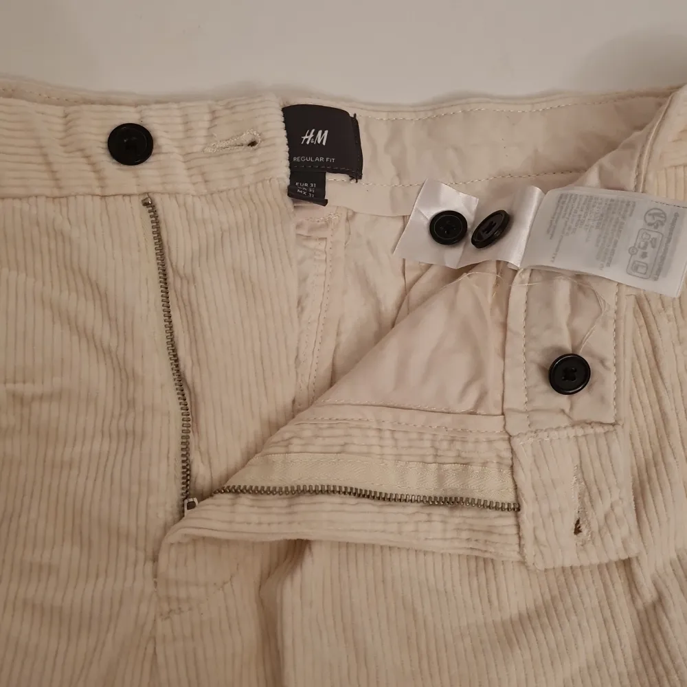 Säljer ett par snygga beige manchesterbyxor från H&M i storlek EUR 31. Byxorna har en regular fit och är perfekta för höst och vinter. De har en dragkedja och knappar framtill samt två fickor bak med knappar. Superbekväma och stilrena!. Jeans & Byxor.