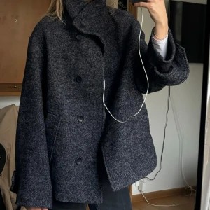 Grå ullkappa - Säljer en stilren grå zara  ullkappa i mycket bra skick. Den har en oversized passform med stora knappar framtill och långa ärmar. Perfekt för höst och vinter.