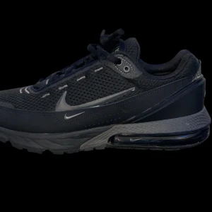 Svarta Nike sneakers - Säljer ett par svarta Nike sneakers i mycket bra skick. De har en stilren design med snörning och en bekväm sula. Perfekta för både vardag och träning. Skorna har en diskret Nike-logga på sidan och är gjorda i syntetmaterial för hållbarhet.