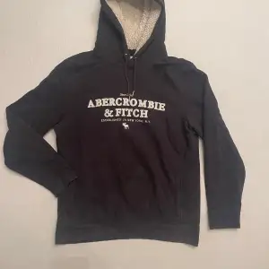 Säljer en svart hoodie med riktigt skön fleece från Abercrombie & Fitch i storlek M. Den har en mysig fleecefodrad huva och tryck på framsidan. Perfekt för kalla dagar och avslappnade stunder. Den är storlek M men passar även S