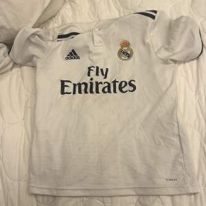  OBS!! Har några små fläckar på fram sidan OBS!!Säljer en vit Real Madrid fotbollströja från Adidas i bra skick. Den har korta ärmar och klubbens emblem på bröstet. På baksidan står det 'Modrić' och nummer 10. Perfekt för fans av laget eller spelaren! ⚽