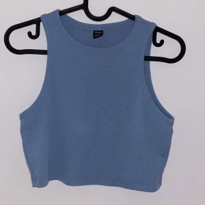 Blå ribbad linnetopp - Snygg blå ribbad linnetopp från Zara i ett mjukt och stretchigt material. Perfekt för sommardagar eller som ett lager under en jacka. Toppen är ärmlös och har en croppad passform som ger en trendig look.