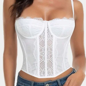 Vit spetskorsett - Snygg vit korsett med spetsdetaljer och justerbara axelband. Perfekt för en festlig kväll eller en romantisk middag. Den har en tight passform som framhäver figuren och en elegant design med hakknäppning bak. Strl L men passar även S/M