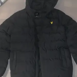 Säljer en svart pufferjacka från Lyle & Scott i storlek 12/13 år. Jackan har en mysig huva och är perfekt för kalla dagar. Den är i mycket bra skick och har en dragkedja framtill. Perfekt för vintern! 🖤