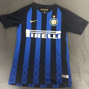 Inter Milan fotbollströja - Säljer en snygg Inter Milan fotbollströja från Nike i klassiskt blått och svart randigt mönster. Tröjan har korta ärmar och Pirelli-loggan på framsidan. Perfekt för alla fans! 💙⚽Nypris 699 använd bara några gånger