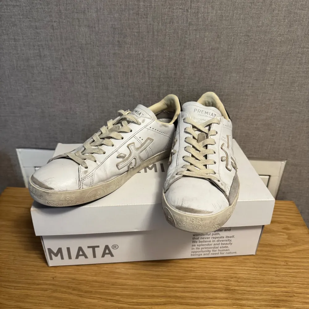 Säljer ett par vita sneakers från Premiata i bra skick. De har en snygg design med snörning och en svart detalj vid hälen. Perfekta för vardagsbruk och ger en stilren look. Sulan är i gott skick och skorna är bekväma att gå i.. Skor.